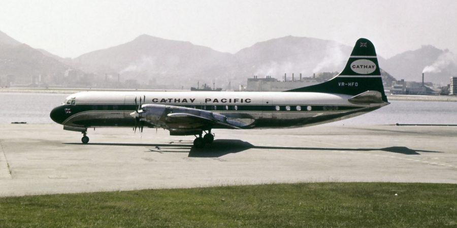 一张颗粒感强烈的复古照片，呈现一架国泰航空飞机停在跑道上，背景是连绵的山峦。